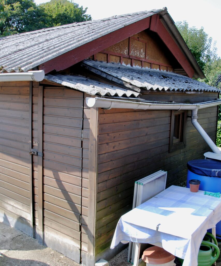 Foto einer alten, braunen Gartenhütte aus Holz mit niedrigerem Anbau