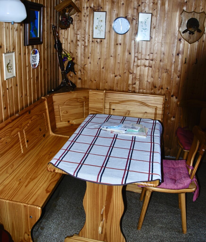 Innenansicht einer mit Holz verkleideten Gartenlaube mit Eckbank