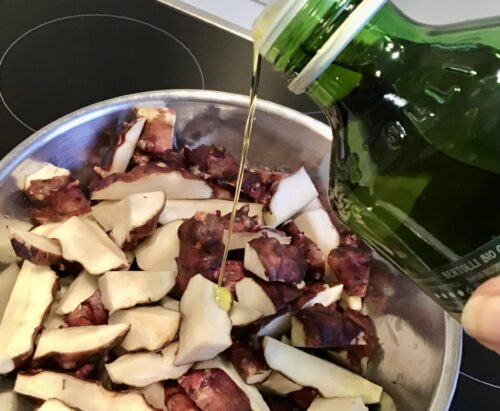 Topinamburstücke in einer Schüssel werden mit Öl begossen